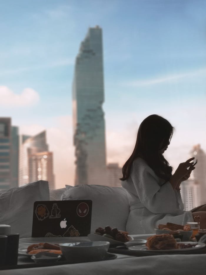 Hello world! A serene morning scene of a woman relaxing with breakfast in a luxurious Bangkok hotel room.
